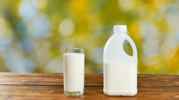 Garrafa de leite e vidro com leite no jardim na mesa de madeira
 - Filmagem, Vídeo