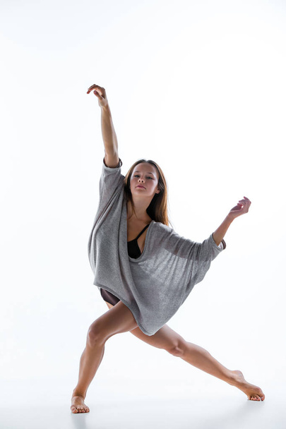 Young beautiful dancer in beige dress dancing on white background - 写真・画像