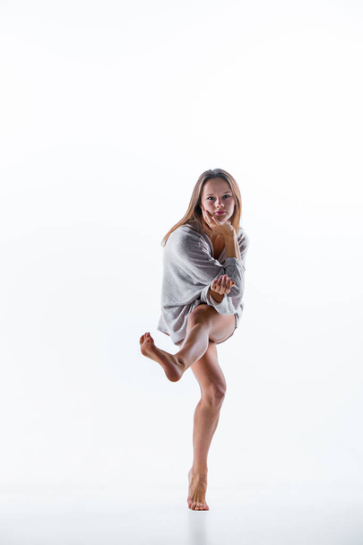 Young beautiful dancer in beige dress dancing on white background - Valokuva, kuva