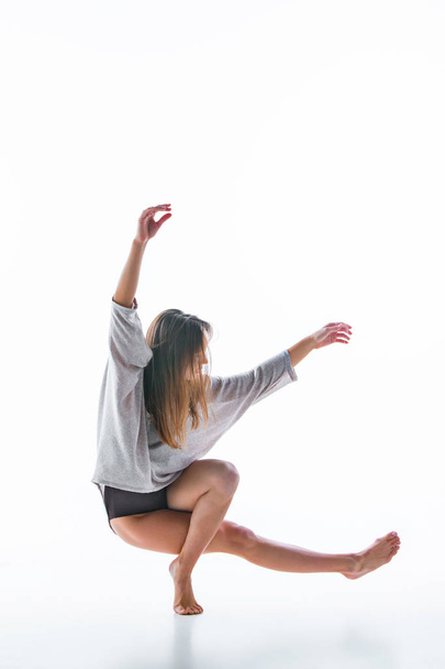 Young beautiful dancer in beige dress dancing on white background - 写真・画像