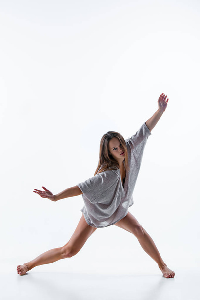 Young beautiful dancer in beige dress dancing on white background - Фото, зображення