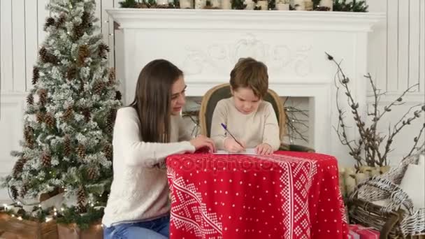 Young mother helping her little son to write a letter to Santa Claus - Metraje, vídeo