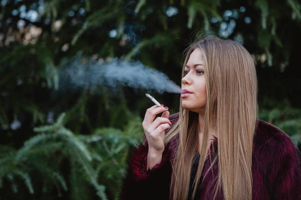 Pretty girl smoking in park - Foto, imagen