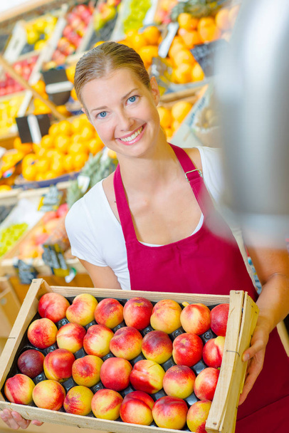 shop assistant holding tray of nectarines - Foto, imagen
