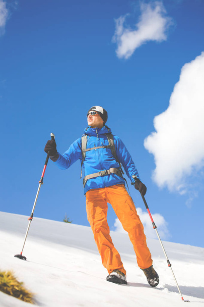 Человек с треккинговыми столбами проходит через снег в горах
. - Фото, изображение