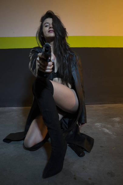 Army brunette girl with gun in a garage  - 写真・画像