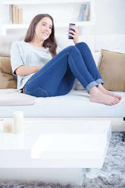 Frau auf Sofa checkt ihr Smartphone - Foto, Bild