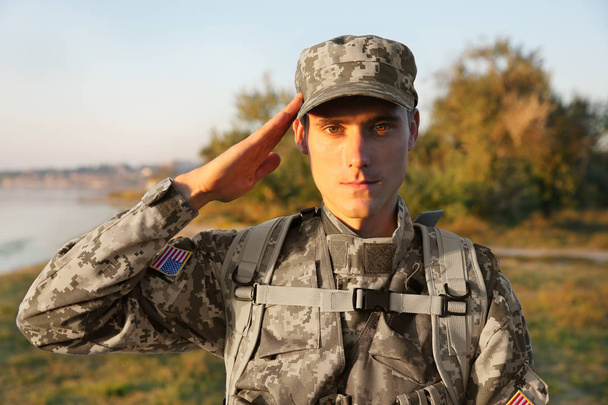 Soldier in camouflage taking salute outdoors - Foto, Imagen
