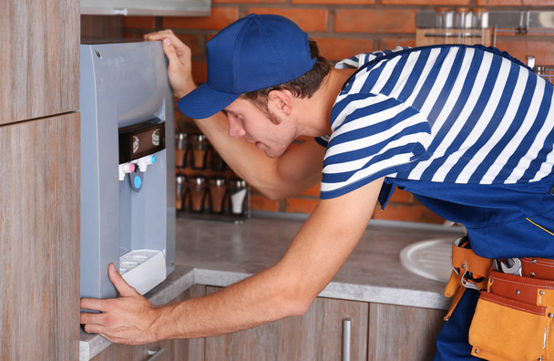 Specialist repairing water cooler at kitchen - Foto, imagen