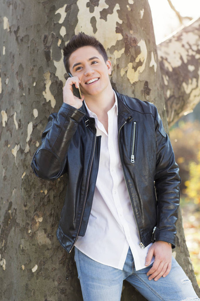 Outdoors, young man talking on phone - Foto, imagen