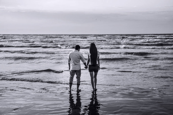 Boldog gazdaság kezét pár hullámok a tengerparton a tengerparton a tengerre vagy a szép pár. Szerelem, a boldogság, a romantikus jelenet. - Fotó, kép