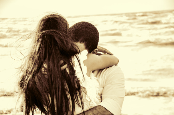 Feliz abrazo pareja en la playa con el mar borroso en el fondo o pareja encantadora en seaside.Love, felicidad, escena romántica
. - Foto, imagen