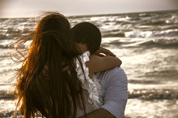 海辺に背景や素敵なカップルにぼやけた海とビーチで幸せなハグのカップル。愛、幸福、ロマンチックなシーン. - 写真・画像
