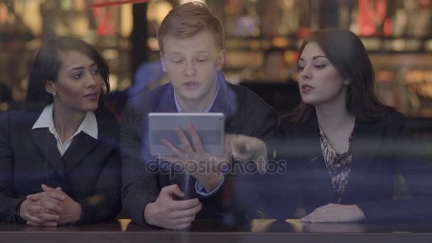 Freunde schauen auf einen Tablet-Computer, unterhalten sich und haben Spaß - Filmmaterial, Video