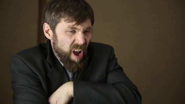 bearded business executive man wears a jacket, yawning and shaking from a cold on a next day after a party - Imágenes, Vídeo