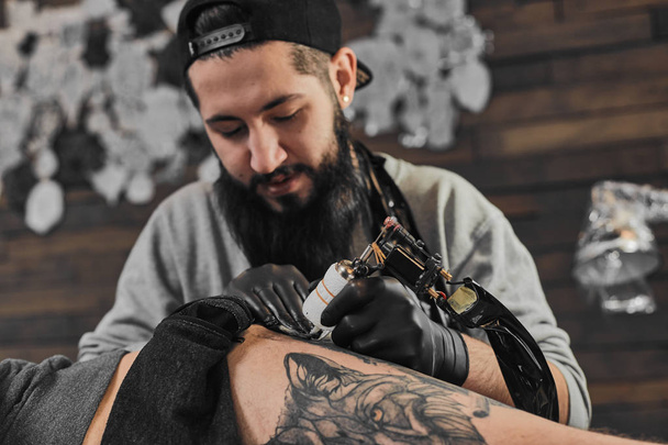 Tattoo master is tattooing in the tattoosalon - 写真・画像