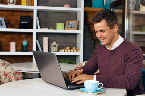Happy young man smiling and works on his laptop - 写真・画像