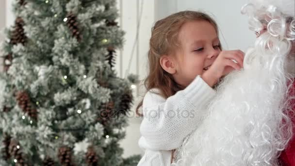 Surprised little girl checking upon Santa beard - Materiał filmowy, wideo