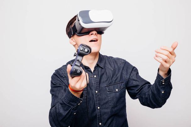 Młody mężczyzna, grając w gry wideo z zestaw wirtualnej rzeczywistości i joystick lub jazdy z pilota zdalnego sterowania. - Zdjęcie, obraz