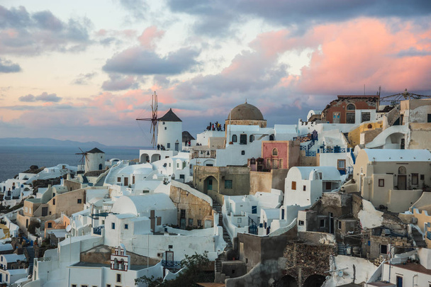 White city on a slope of a hill at sunset, Oia, Santorini, Greec - 写真・画像