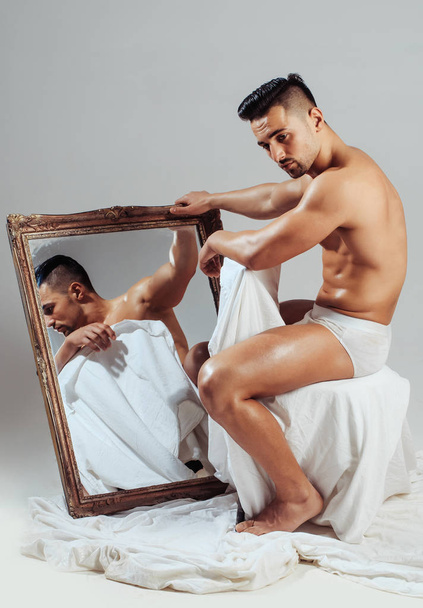 Handsome bodybuilder looks at mirror - Photo, image