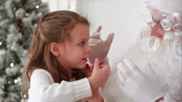 Little girl showing Santa Claus a magic trick with a disappearing finger - Materiał filmowy, wideo