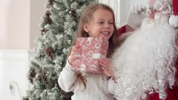 Happy little smiling girl trying to guess what is inside her christmas gift from Santa - Séquence, vidéo