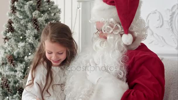 Litlle girl shaking her present from Santa trying to guess what is inside - Кадри, відео