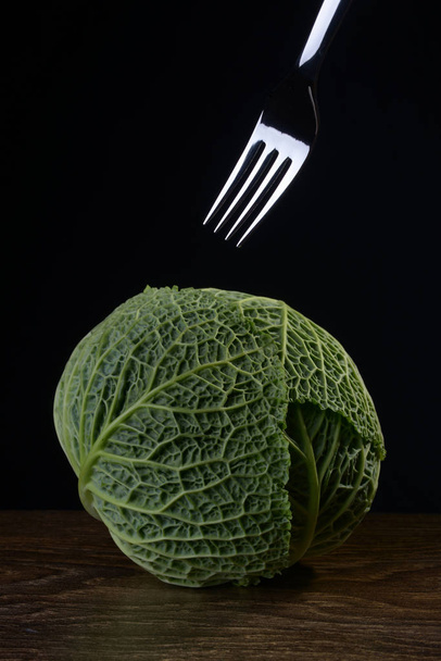 Ripe green savoy cabbage fork on a black background. - 写真・画像