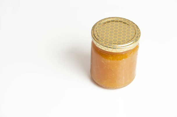 Glass jar of honey on white background - Foto, afbeelding