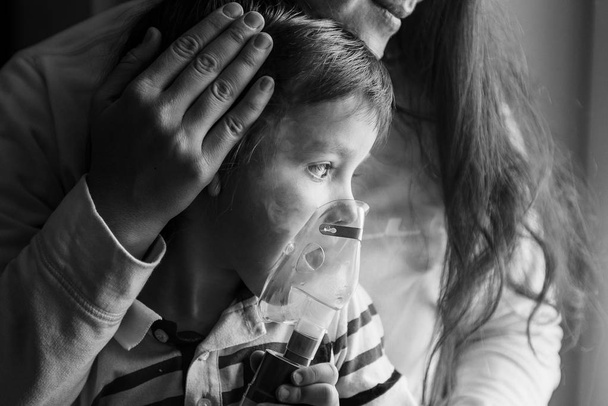 Young woman with son doing inhalation  a nebulizer at home - Photo, Image