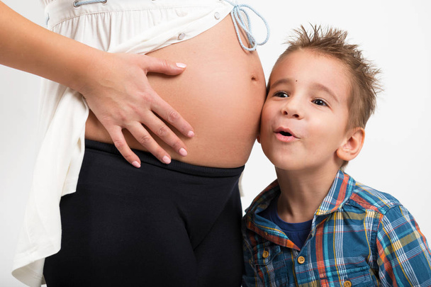 Portret dziecka i kobiety w ciąży. Słucha co dzieje się w brzuchu matki. Zbliżenie zdjęcie - Zdjęcie, obraz