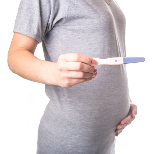 Girl with tummy holding pregnancy test. isolated - Photo, Image