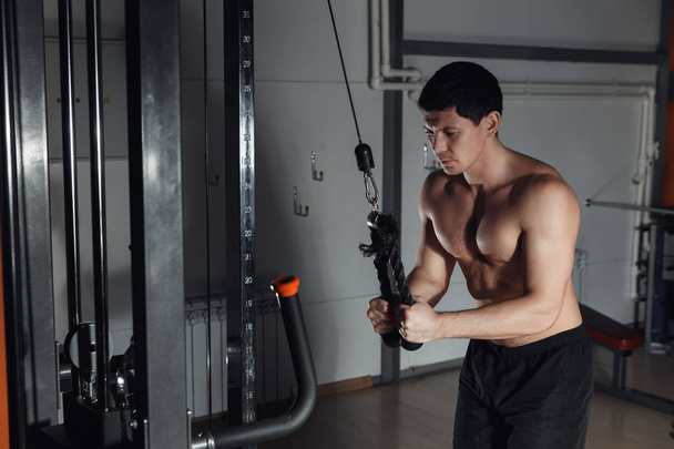young athletic man doing exercise for triceps on block exerciser in gym. - Photo, Image