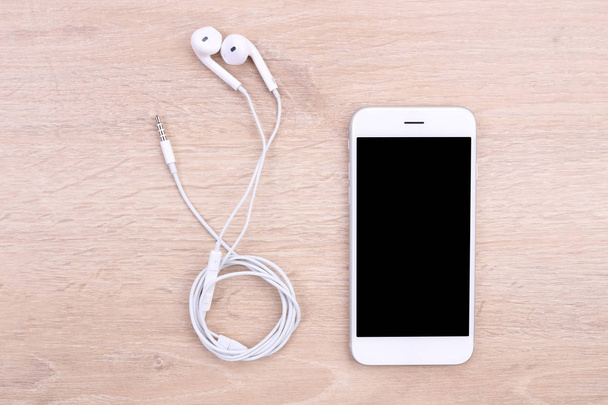 Maketa smartphone s sluchátka na dřevěné pozadí - Fotografie, Obrázek