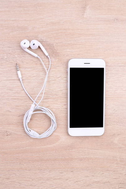maqueta de smartphone con auriculares sobre fondo de madera
 - Foto, imagen