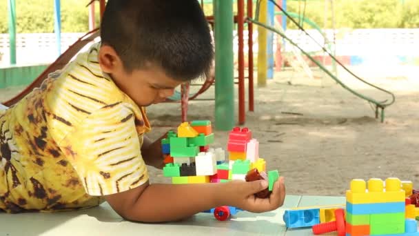 Malý roztomilý chlapec asijské hrát s plastových stavebních bloků v parku - Záběry, video