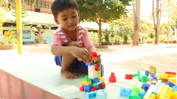 Poco lindo asiático chico jugando con plástico bloques de construcción en el parque
 - Imágenes, Vídeo