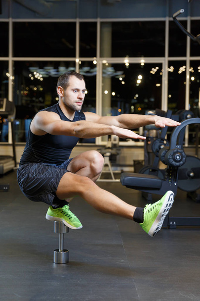 Athletic guy doing exercise with weights at the gym - 写真・画像