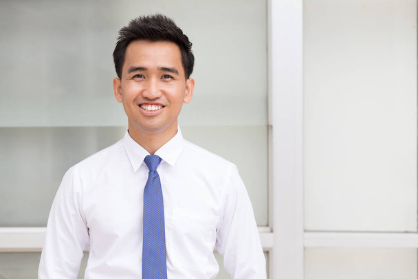 Азиатский бизнесмен стоит и улыбается
 - Фото, изображение