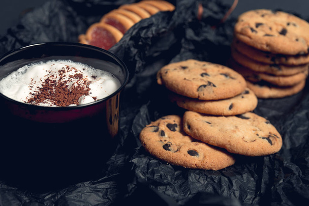Tasse de café, cappuccino avec biscuits au chocolat et biscuits sur fond de table noire. Après-midi, pause. Petit déjeuner
. - Photo, image