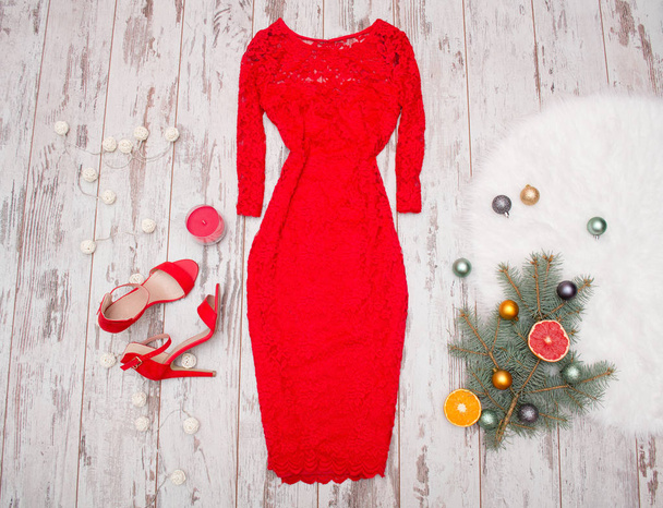 Robe en dentelle rouge élégante, chaussures rouges sur un fond en bois, branche de sapin avec ornements et agrumes. concept de mode
 - Photo, image