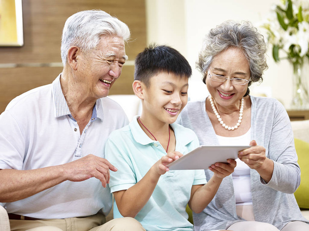 Azjatycka rodziców grand i grand dziecka w domu za pomocą tabletu - Zdjęcie, obraz