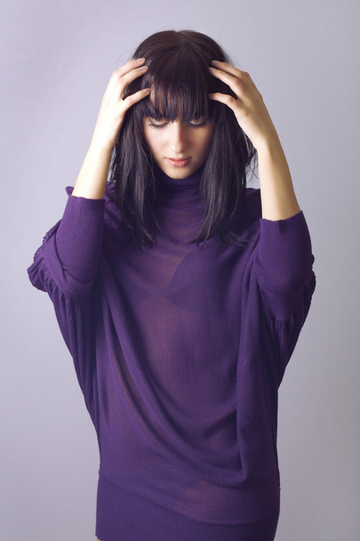 Attractive fashionable woman in purple dress holding hands on hair. isolate - Foto, Bild