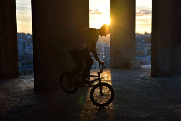 Чоловік їде на велосипеді bmx, виконуючи трюк проти заходу сонця. Екстремальні види спорту
 - Фото, зображення