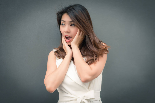 Surprised and excited Asian woman on gray wall background - Photo, Image