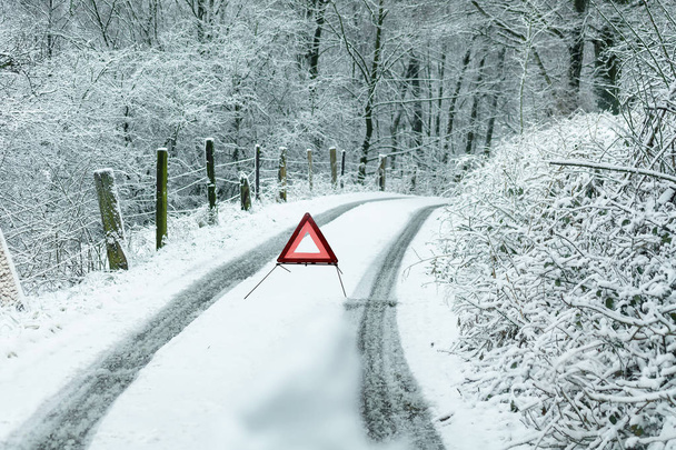 Camino después de fuertes nevadas con un triángulo de advertencia
. - Foto, imagen