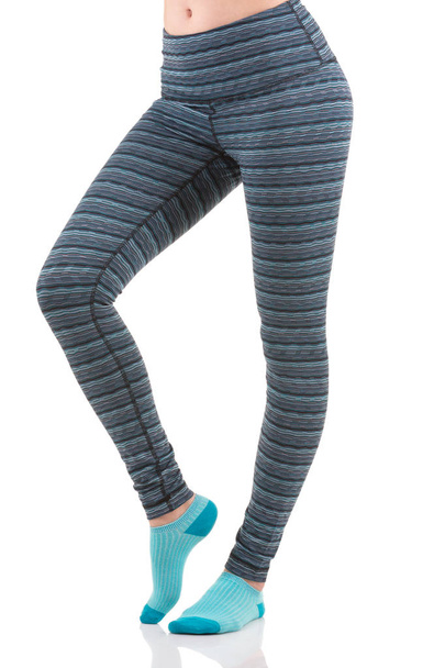 Vue latérale rapprochée des jambes femme en forme échauffement dans des leggings de sport rayés colorés portant des chaussettes bleues
 - Photo, image