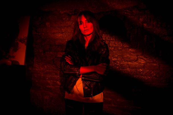 красивая женщина в кожаной куртке против кирпичной стены темноты
 - Фото, изображение
