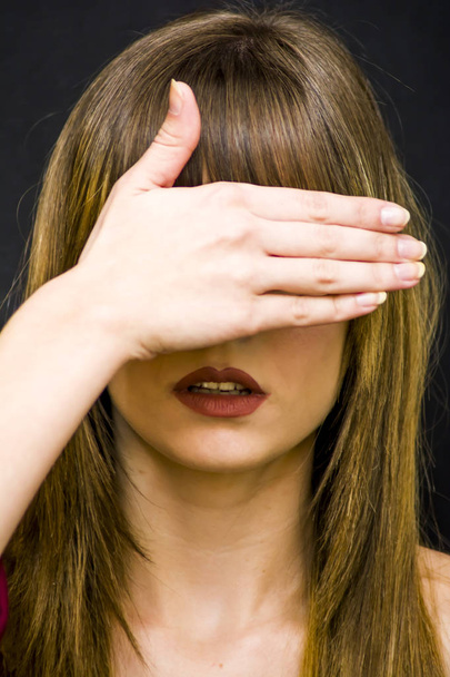 Beauty Woman  covering her eyes with her hand Portrait over Blac - Fotó, kép